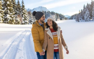 Junges Paar im Winter, eng umschlungen, lächelnd – Symbol für Kinderwunsch im Winter und Hoffnung mit TCM